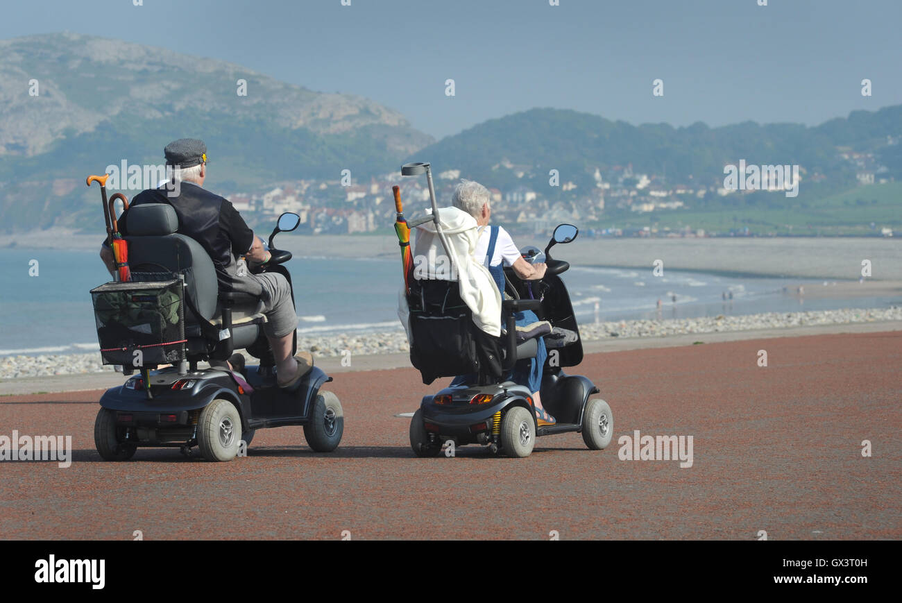 PEOPLE IN MOBILITY SCOOTERS ON THE PROMENADE AT LLANDUDNO NORTH WALES RE DISABILITY ELDERLY RETIREMENT PENSIONERS SEASIDE UK Stock Photo