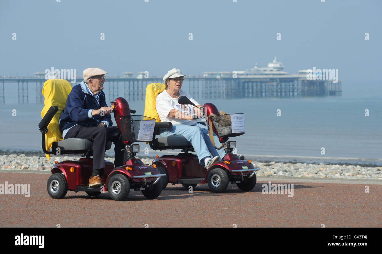 PEOPLE IN MOBILITY SCOOTERS ON THE PROMENADE AT LLANDUDNO NORTH WALES RE DISABILITY ELDERLY RETIREMENT PENSIONERS SEASIDE UK Stock Photo