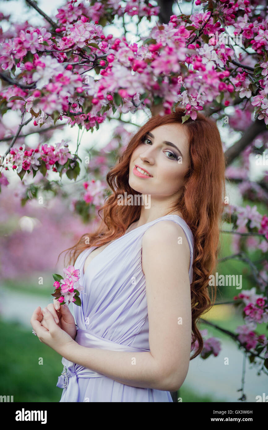 Closeup portrait of beautiful female  in fresh pink floral garden, warm sunset light, spring nature, vacation and leisure concept Stock Photo