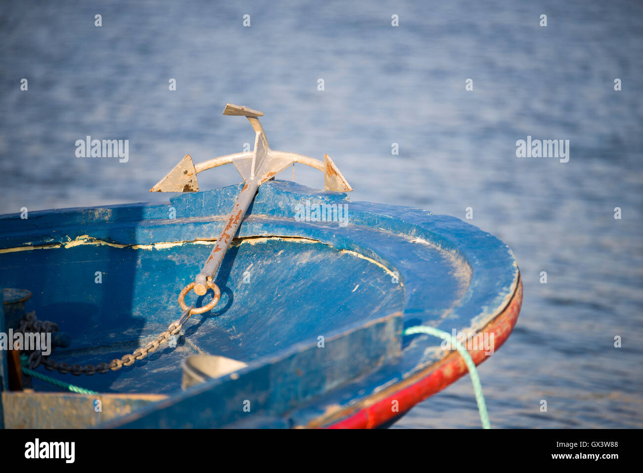 Anchor and a blue fishing boat Stock Photo - Alamy