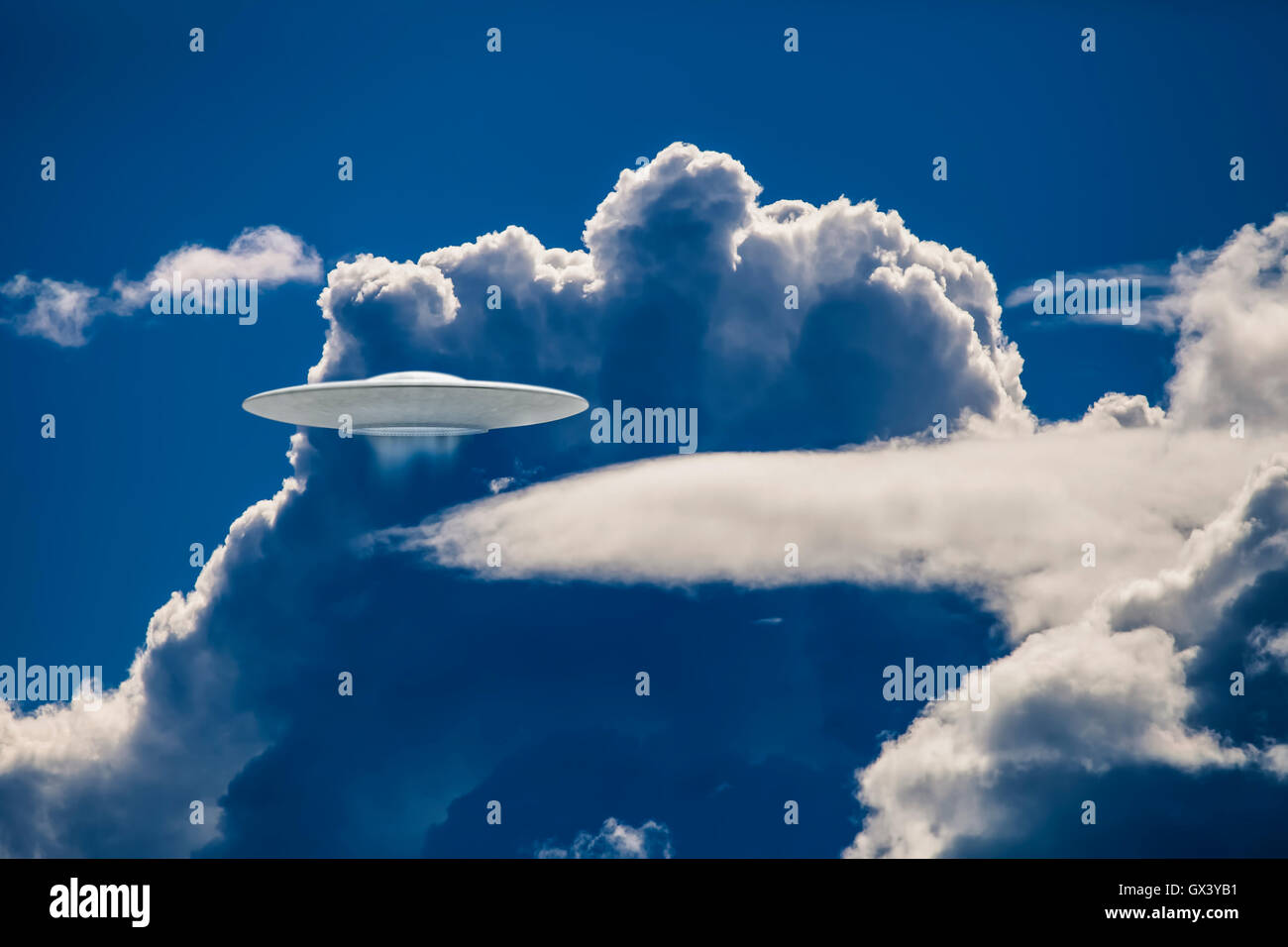 UFO spaceship in dramatic clouds with blue tones. Stock Photo