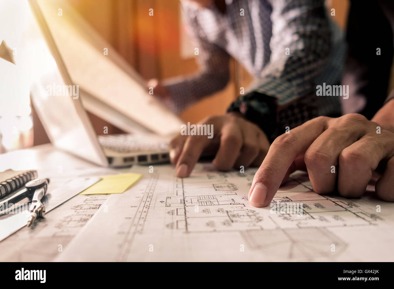 Two colleagues discussing data working tablet, laptop with on on architectural project at construction site at desk in office Stock Photo