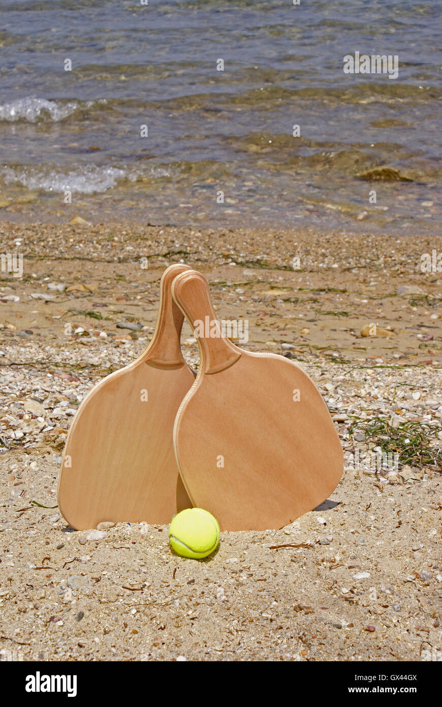 Set for a game of beach tennis on the background of sea and mountains  close-up. Wooden rackets and yellow ball in the sand Stock Photo - Alamy