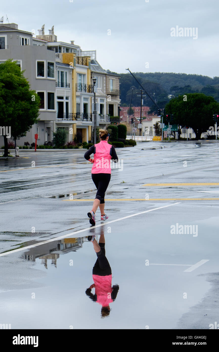 Runner in pink reflected in a puddle in San Francisco California USA Stock Photo