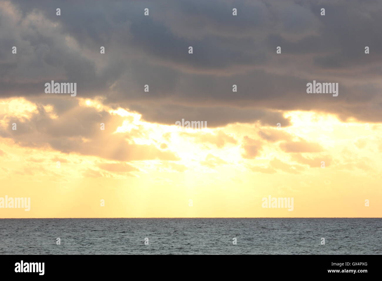 a beautifully moody sky with the sun behind the clouds, at sunset, with the sea Stock Photo