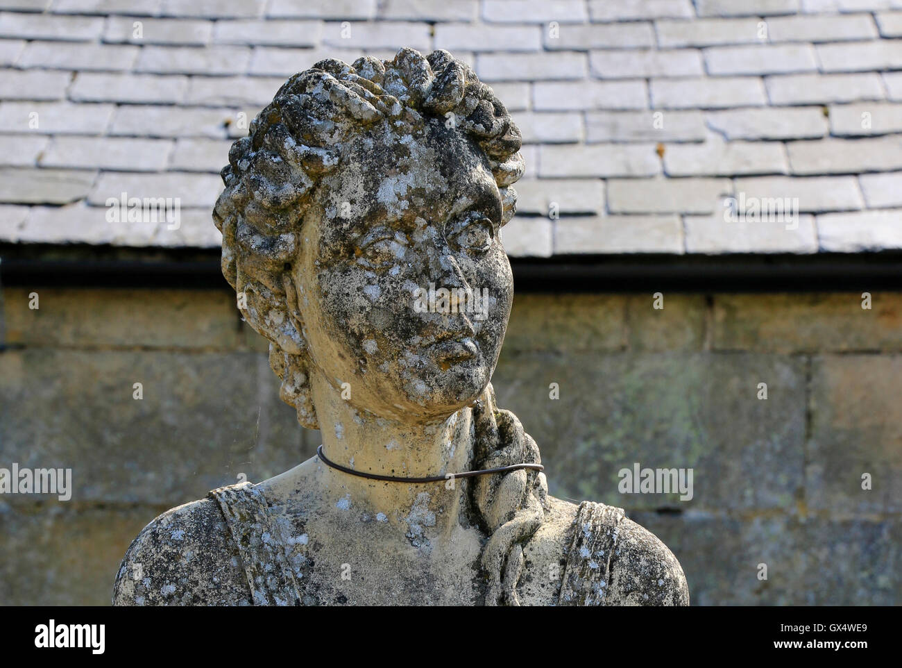 weathered stone statue of a female head and shoulders, a garden ornament Stock Photo