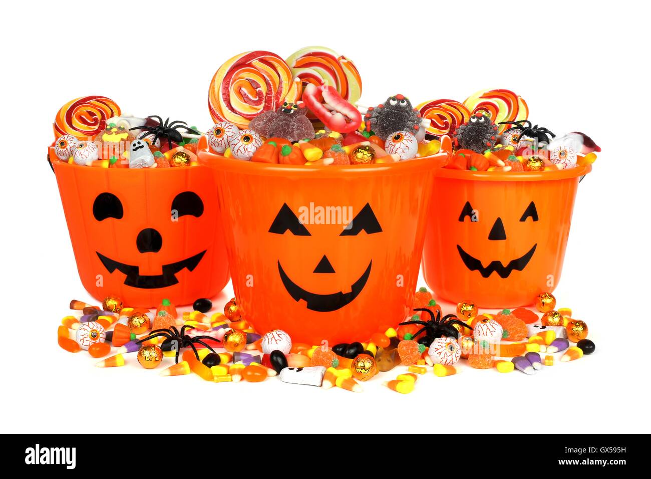 Group of Halloween Jack o Lantern pails with pile of candy over white ...