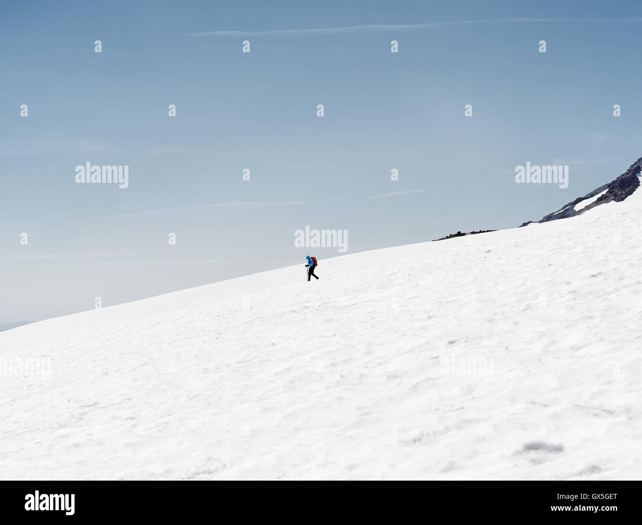 A lone hiker on the snow covered trail to Mt. Rainier's summit Stock Photo