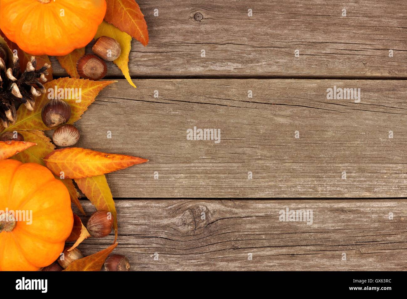 Autumn side border of pumpkins and leaves against a rustic wood background Stock Photo