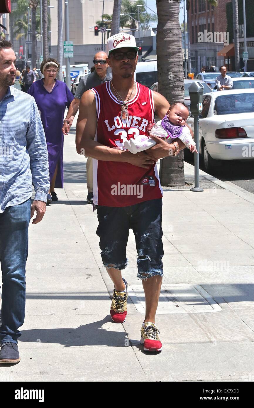 T.I., wearing a Clevland Cavaliers cap and Kobe Bryant Lower Merion  basketball jersey, out for a walk with his newborn daughter on a sunny day  in Beverly Hills Featuring: T.I., Heiress Harris