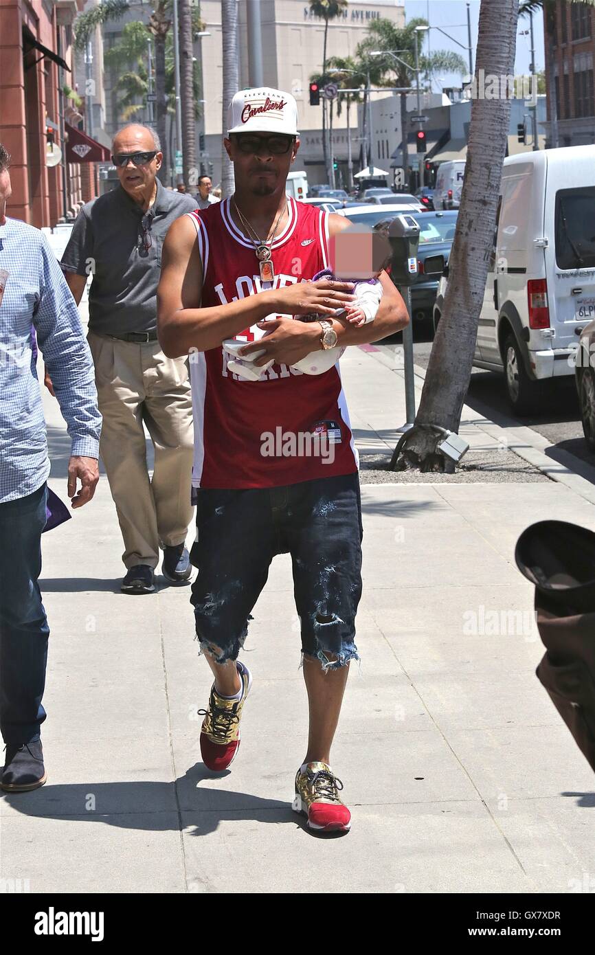 T.I., wearing a Clevland Cavaliers cap and Kobe Bryant Lower Merion basketball  jersey, out for a walk with his newborn daughter on a sunny day in Beverly  Hills Featuring: T.I., Heiress Harris
