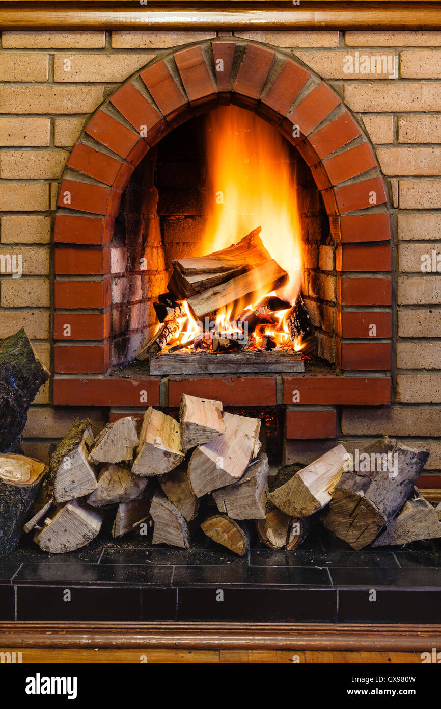 wood logs and fire in indoor brick fireplace in country cottage Stock Photo