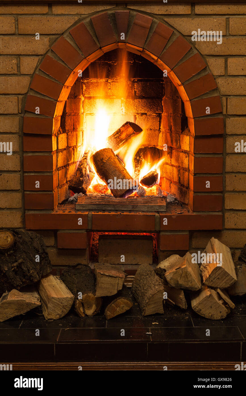 wooden logs and fire in fireplace in country cottage Stock Photo