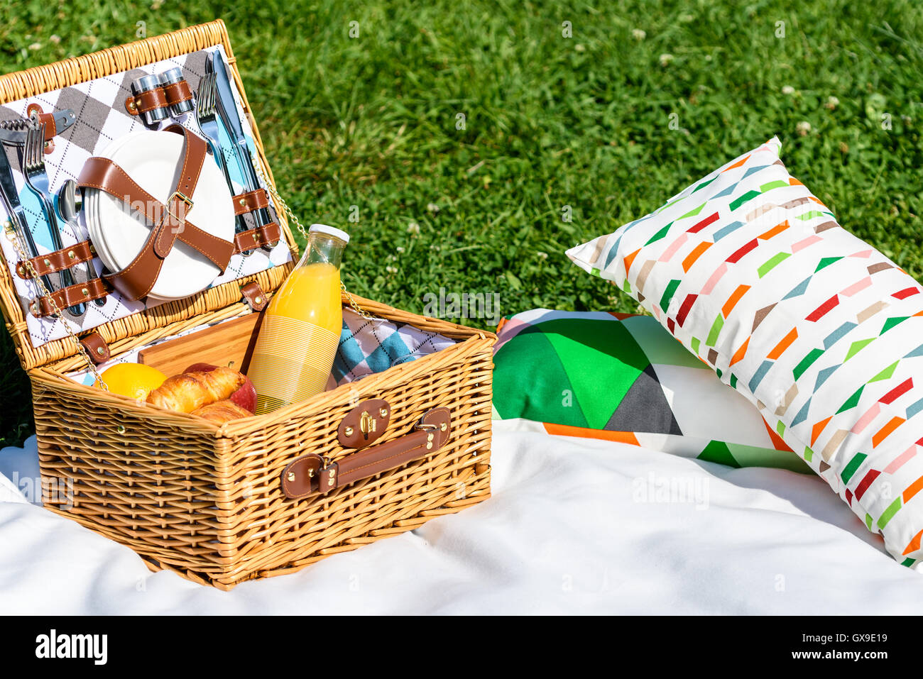 Picnic Basket Food On White Blanket With Pillows In Summer Stock Photo ...
