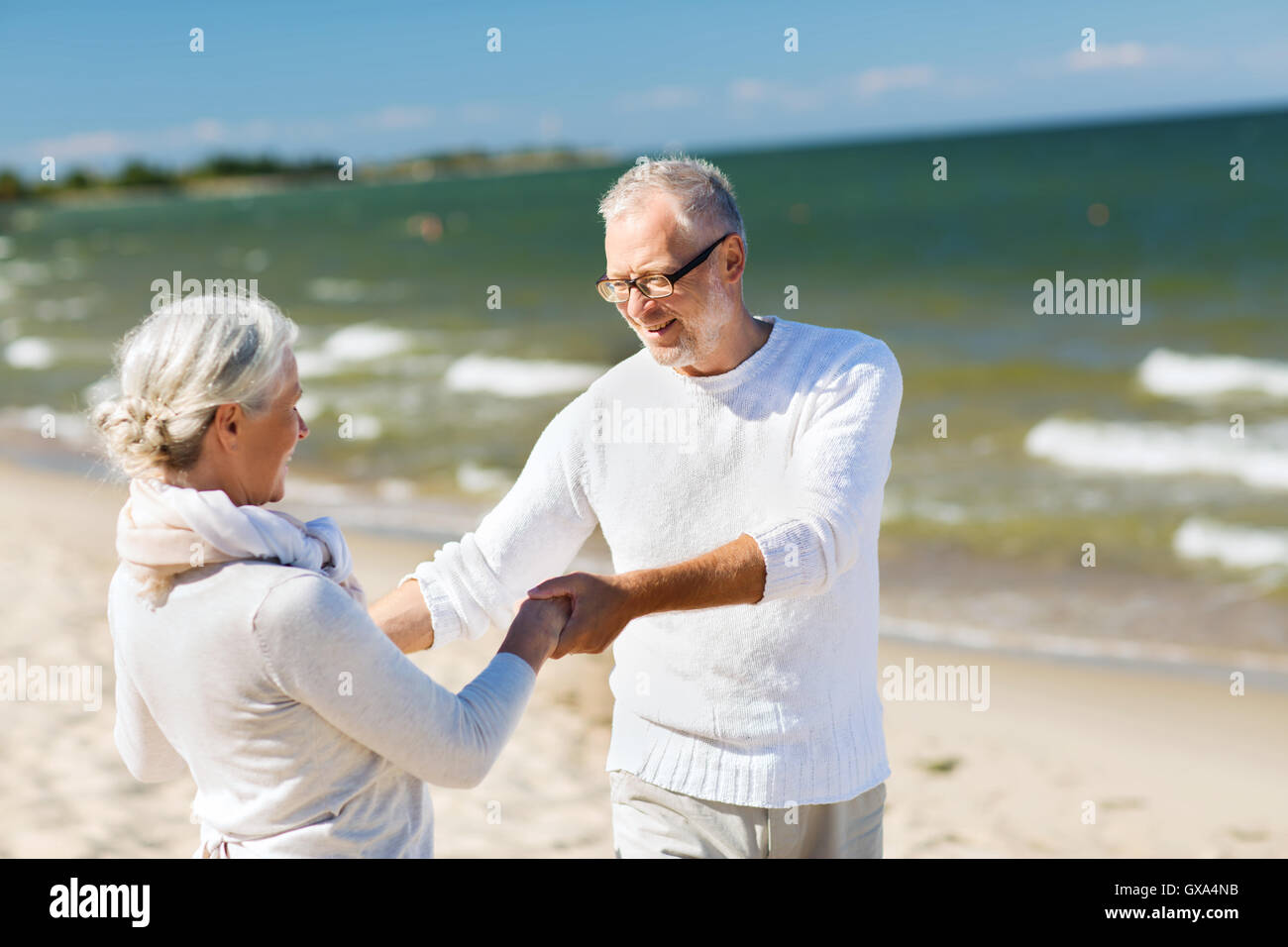 happy senior couple holding hands on summer beach Stock Photo - Alamy
