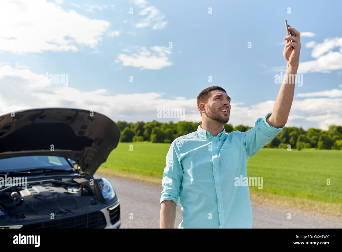 man with smartphone and broken car at countryside Stock Photo