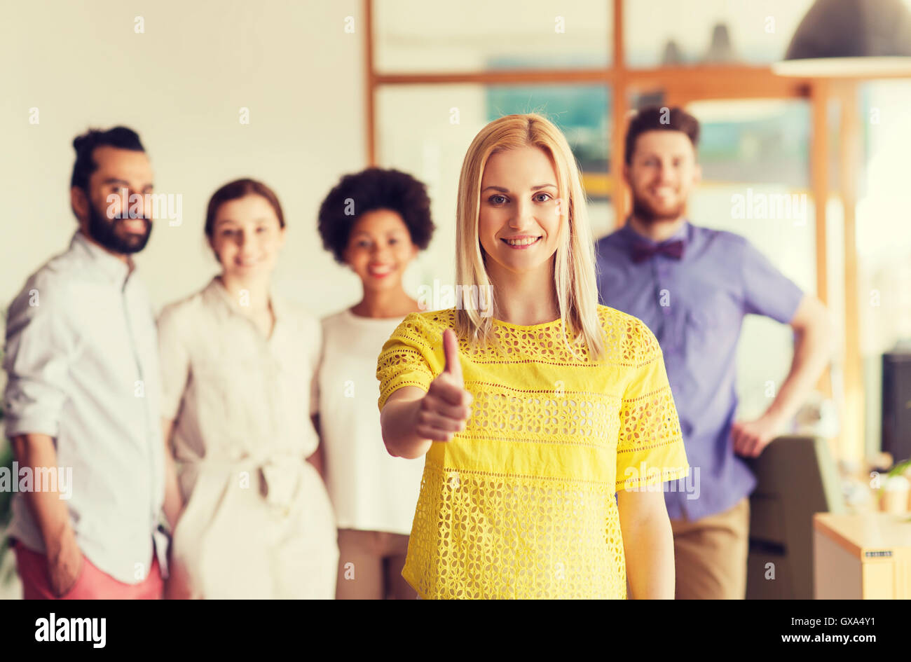 woman showing thumbs up over creative office team Stock Photo - Alamy
