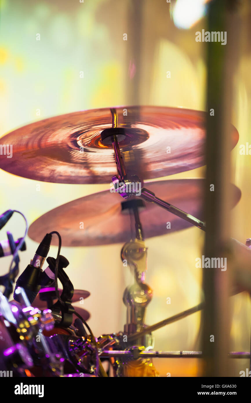 Cymbals in drum set on a stage with colorful illumination, rock music vertical photo background with tonal correction filter Stock Photo