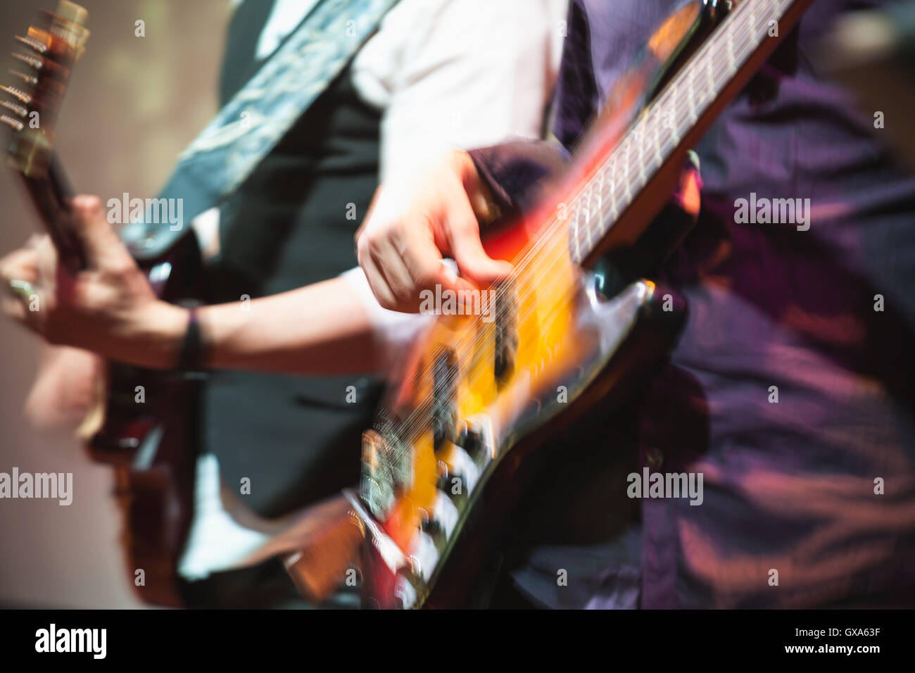 Old style rock music background, guitar players on a stage with colorful illumination, blurred photo with selective focus and re Stock Photo