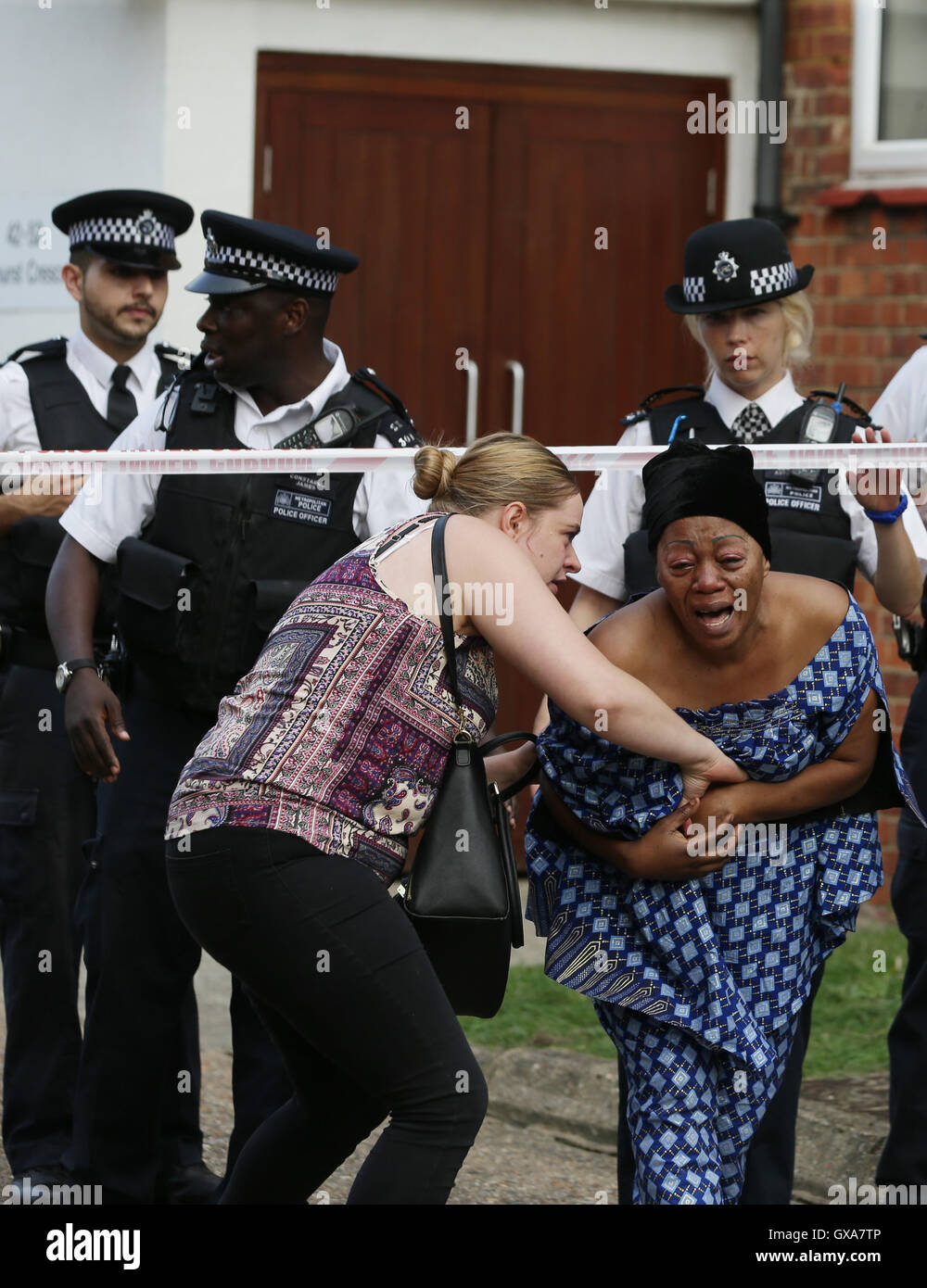 Family members outside flats in in Elmshurst Crescent in East Finchley, north London where Anny Ekofo, 52, and her nephew Bevely, 21, where found dead with gunshot wounds. Stock Photo