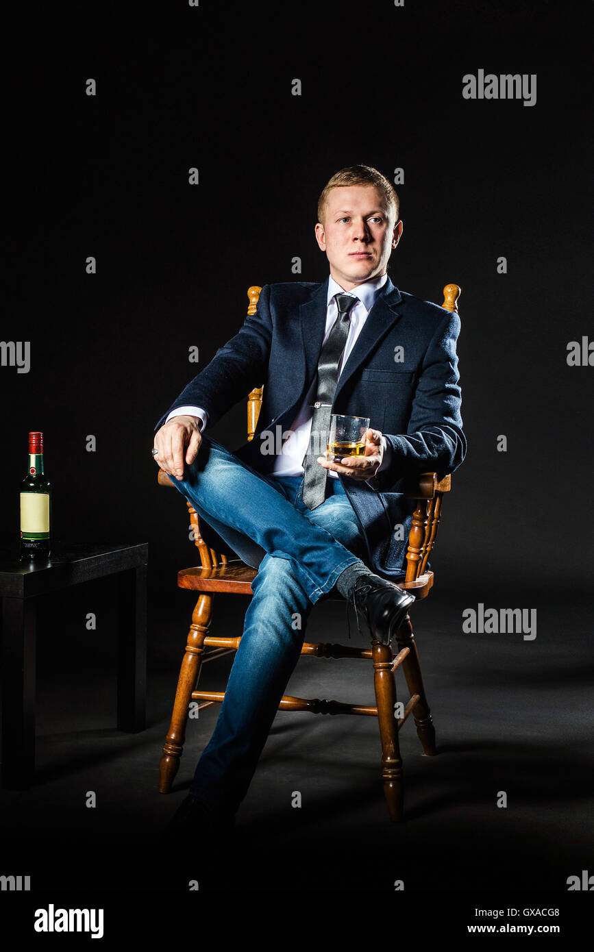 Portrait of serious elegant handsome young man in classic suit toasting with glass  alcohol on black background Stock Photo