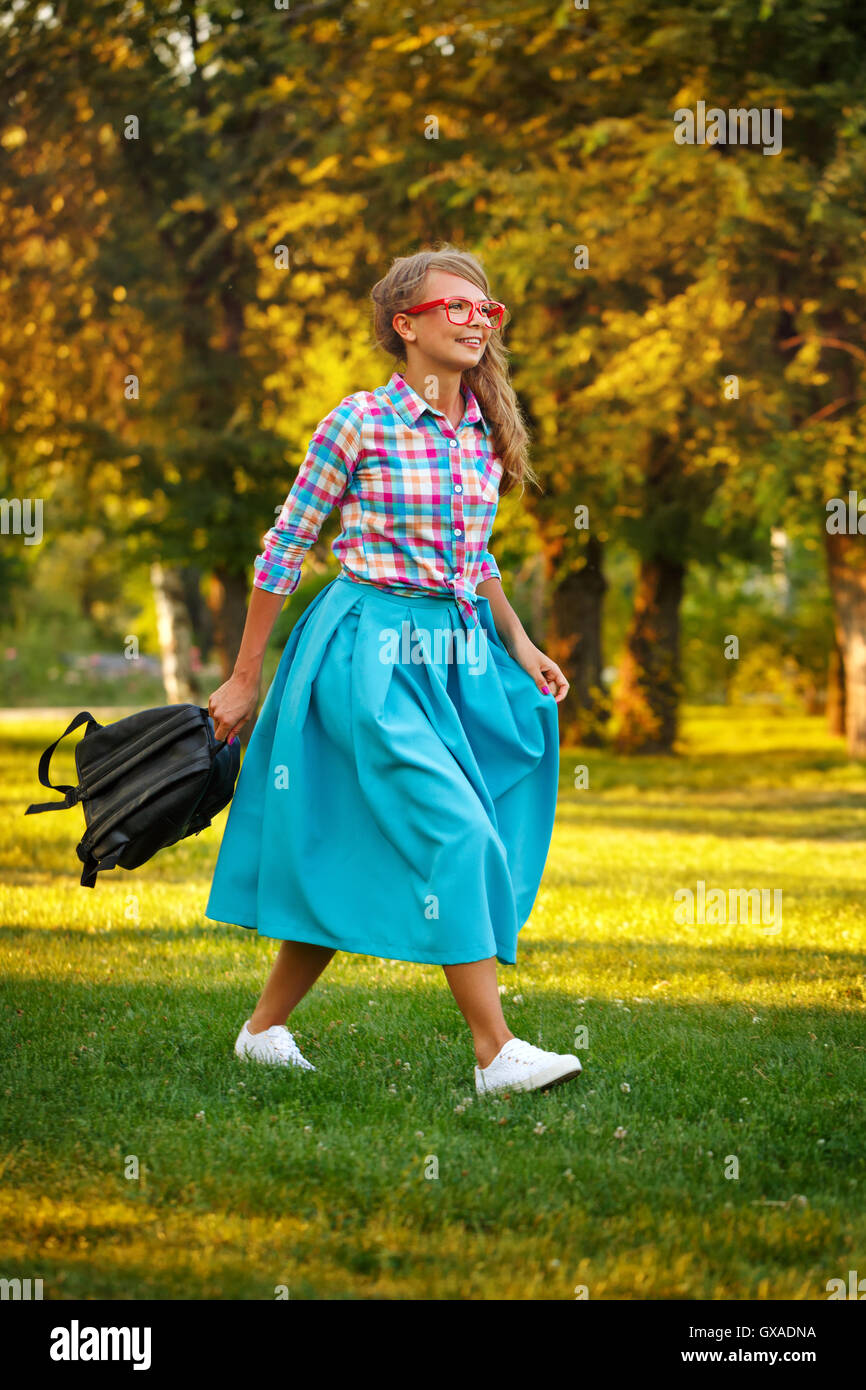 Young girl walking with a backpack in the hands in a city park. Outdoor ...