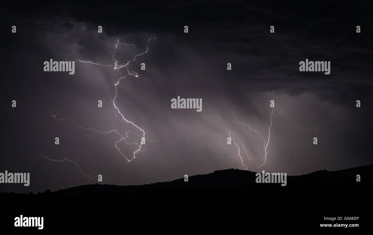 Lightning strike over mountain range with clouds Stock Photo