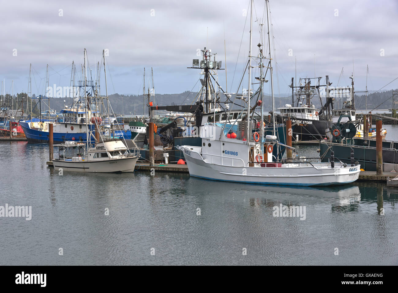 Fishing vessels with raised outriggers moored in Newport bay marina Oregon. Stock Photo