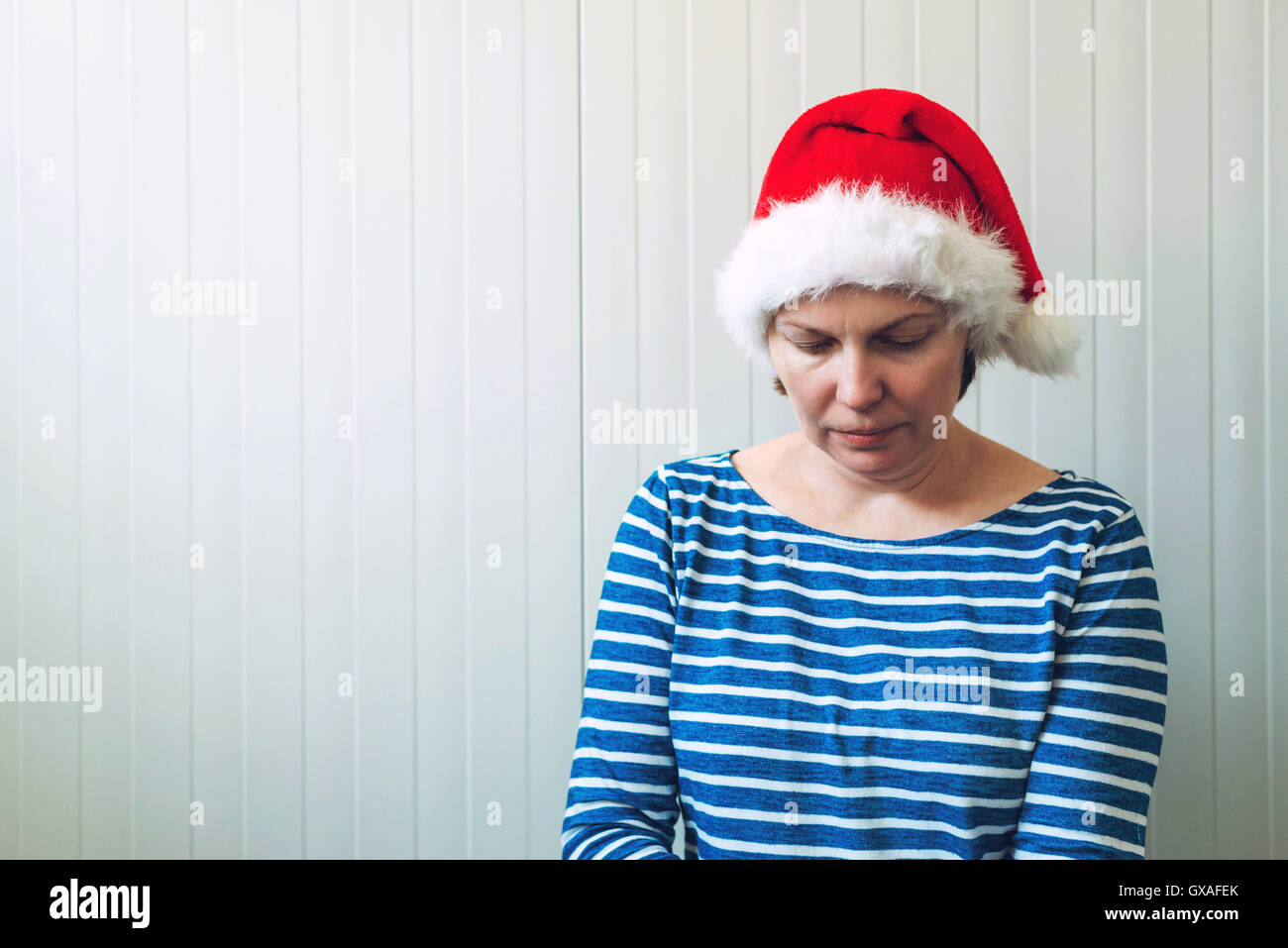 Disappointed woman with Christmas Santa Claus hat suffering from holiday depression, sad and lonely woman waiting New Year all l Stock Photo