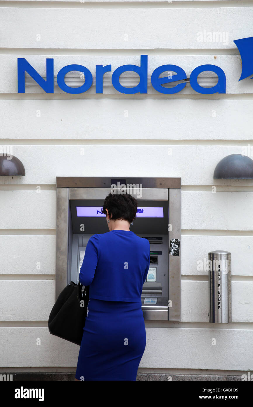 Blue dressed woman make a withdravel from Nordea cash point Stock Photo
