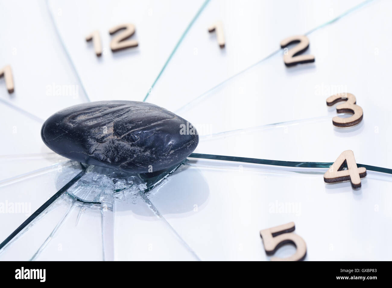 Deadline concept. Black stone on shattered glass clock face Stock Photo