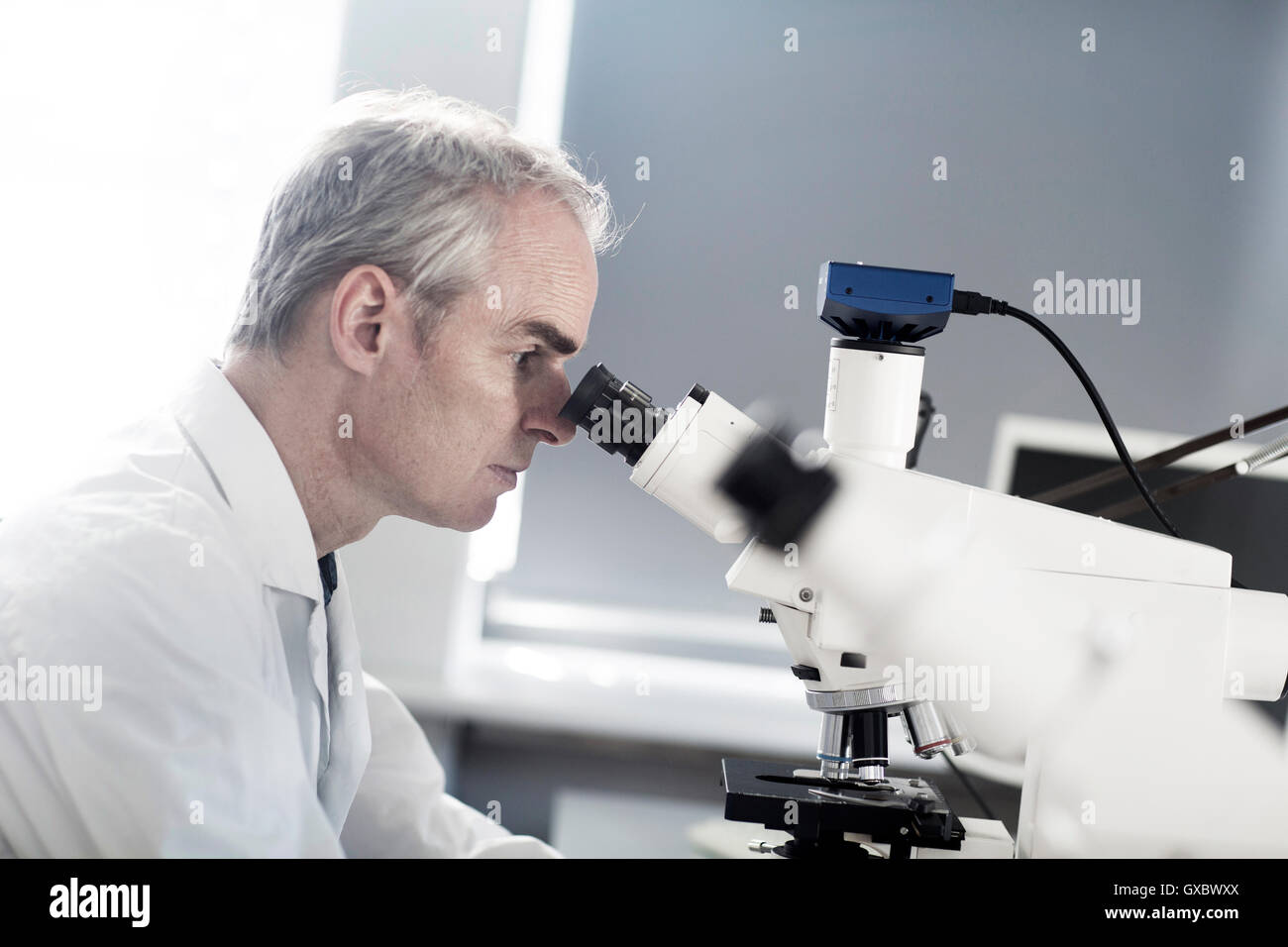Male meteorologist looking through microscope in weather station