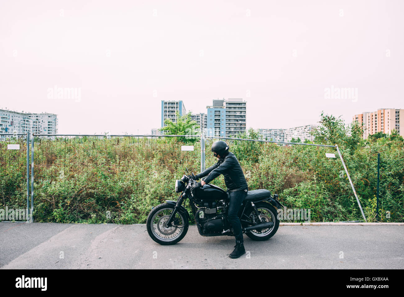Mature male motorcyclist wearing black sitting on motorcycle on road Stock Photo
