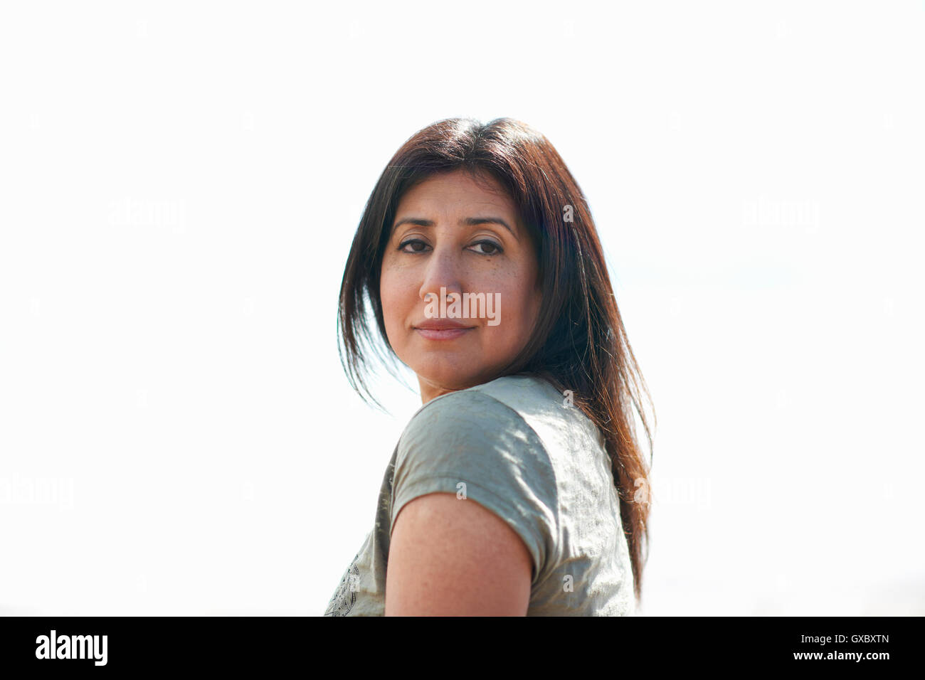Woman with long brown hair looking over her shoulder,  Devon, UK Stock Photo