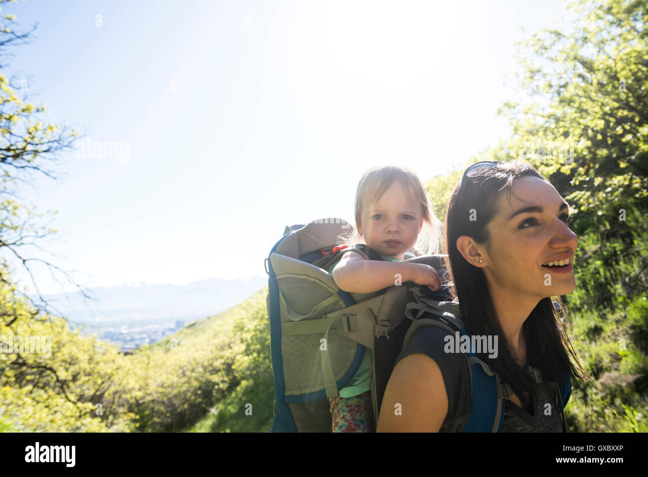Mother carrying young daughter, hiking the Bonneville Shoreline Trail in the Wasatch Foothills above Salt Lake City, Utah, USA Stock Photo