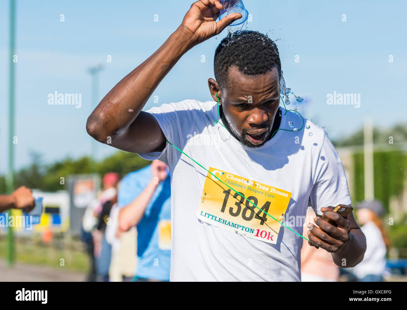 Man cooling off with water while running in a race. Stock Photo