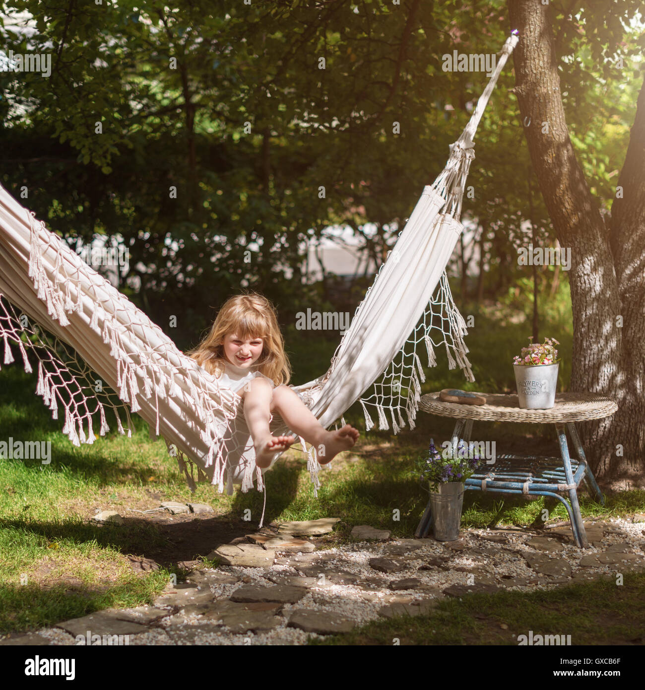 Little girl swinging in a hammock and having fun outdoor. Child playing