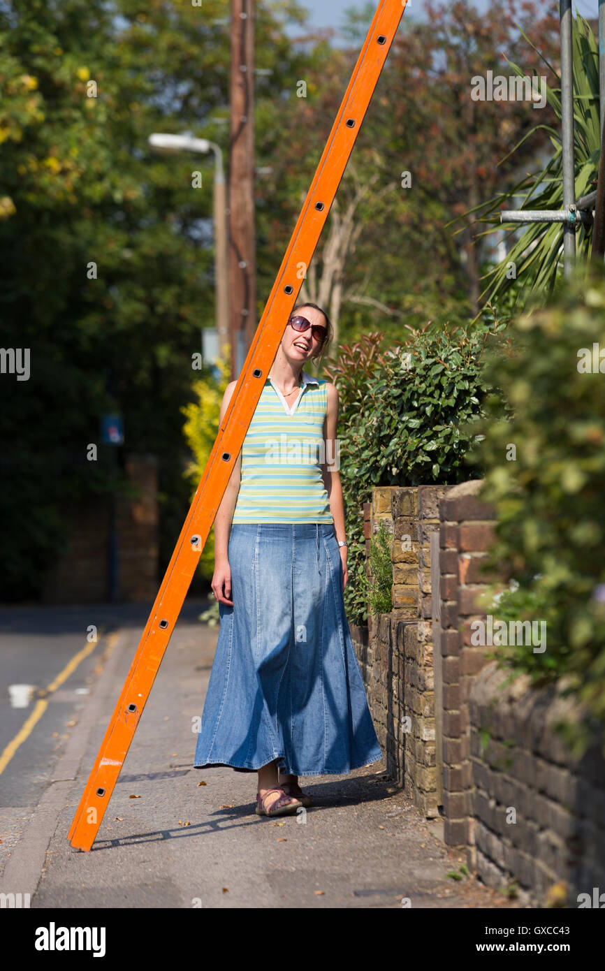 Pedestrian / lady / young woman / people / person walking under a ladder and risking bad luck, in Twickenham, Greater London. UK Stock Photo