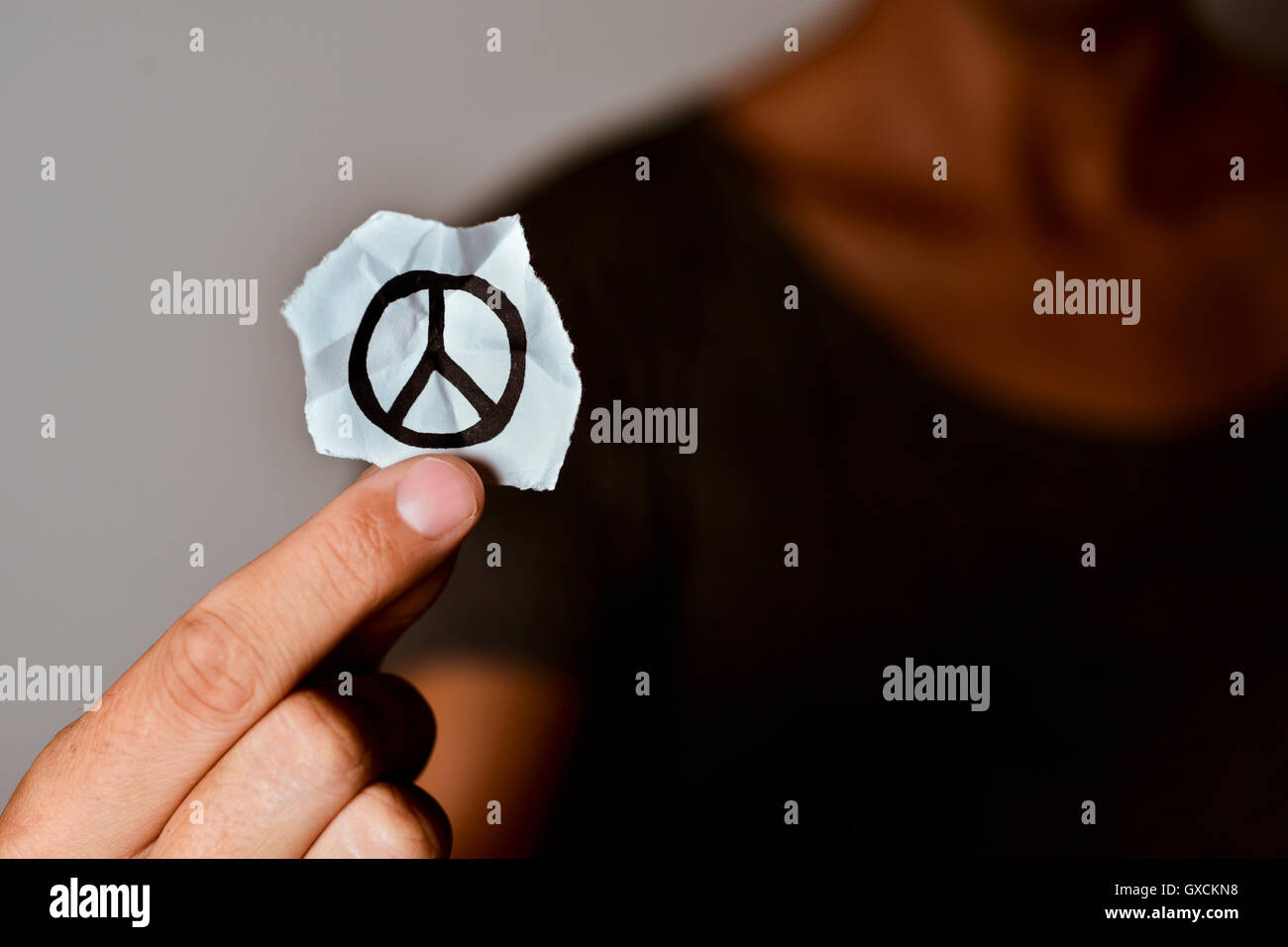 closeup of a young man showing a piece of paper with a peace symbol drawn in it Stock Photo