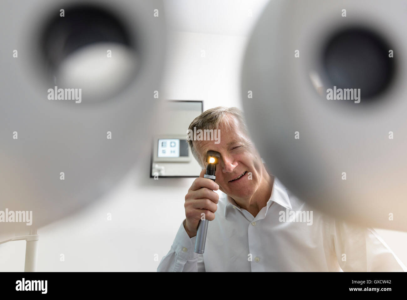 Optician looking into patient's eyes at small business opticians Stock Photo