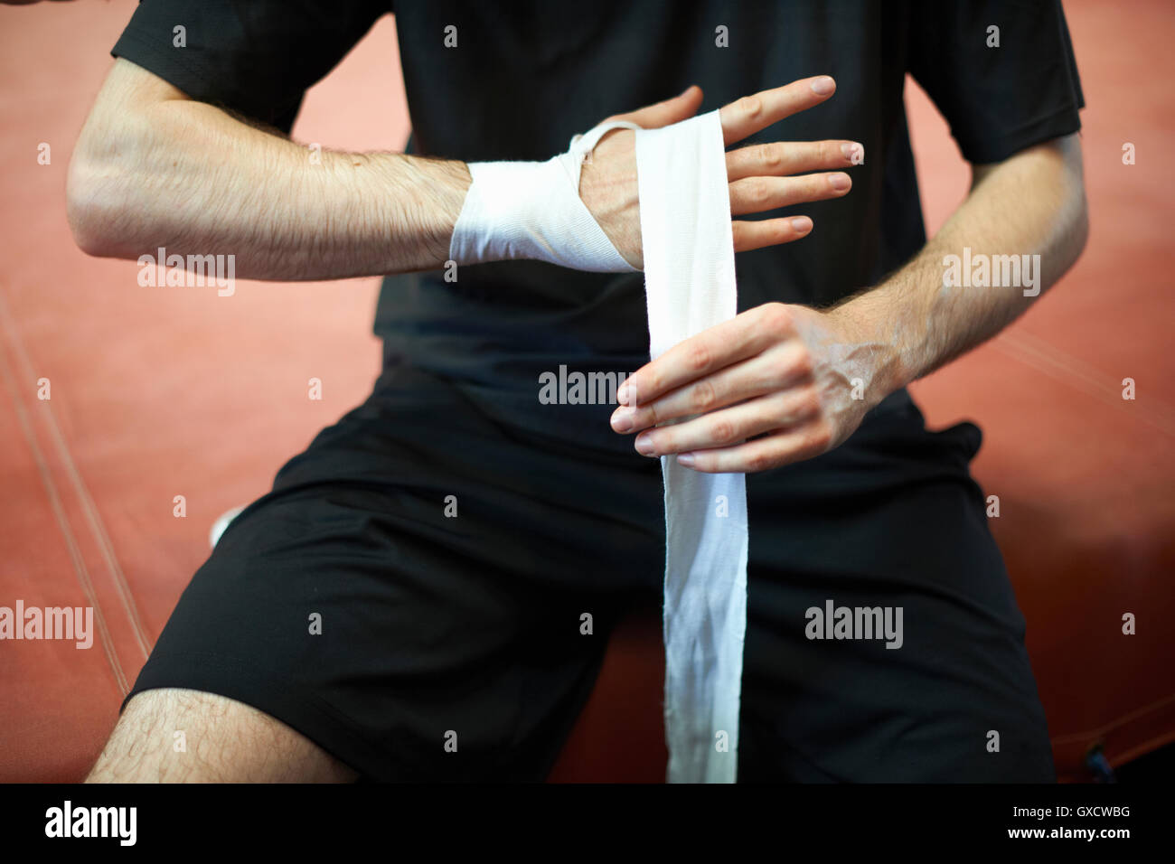 Boxer bandaging hands before putting on gloves, mid section Stock Photo