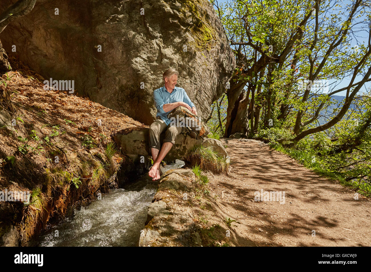 Mature sitting by stream, Meran, South Tyrol, Italy Stock Photo