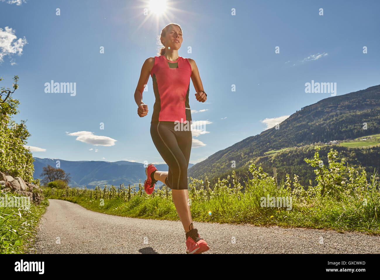 Young woman running along rural road, Meran, South Tyrol, Italy Stock Photo