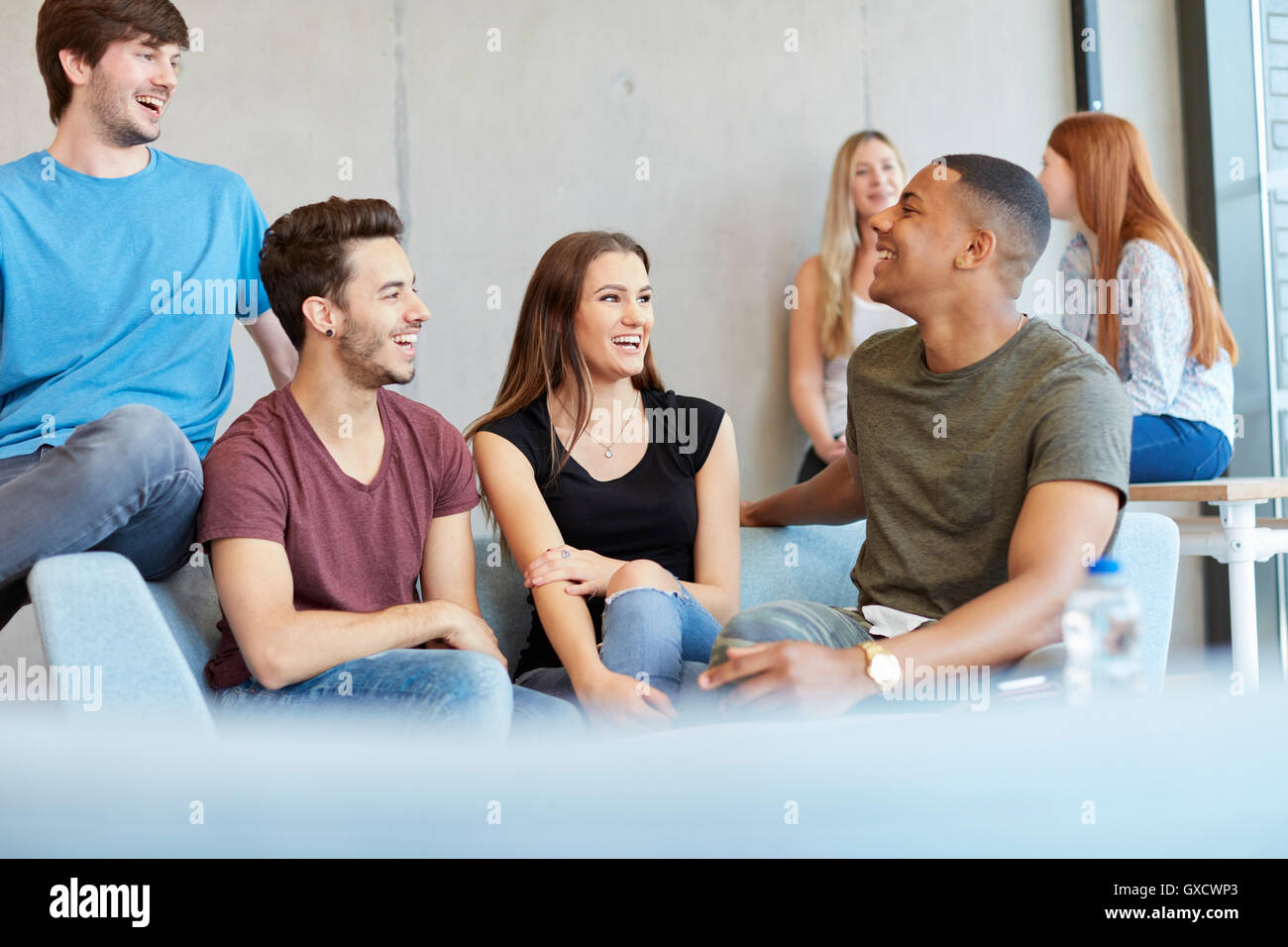 Group of young male and female students sitting on study space sofa chatting at higher education college Stock Photo