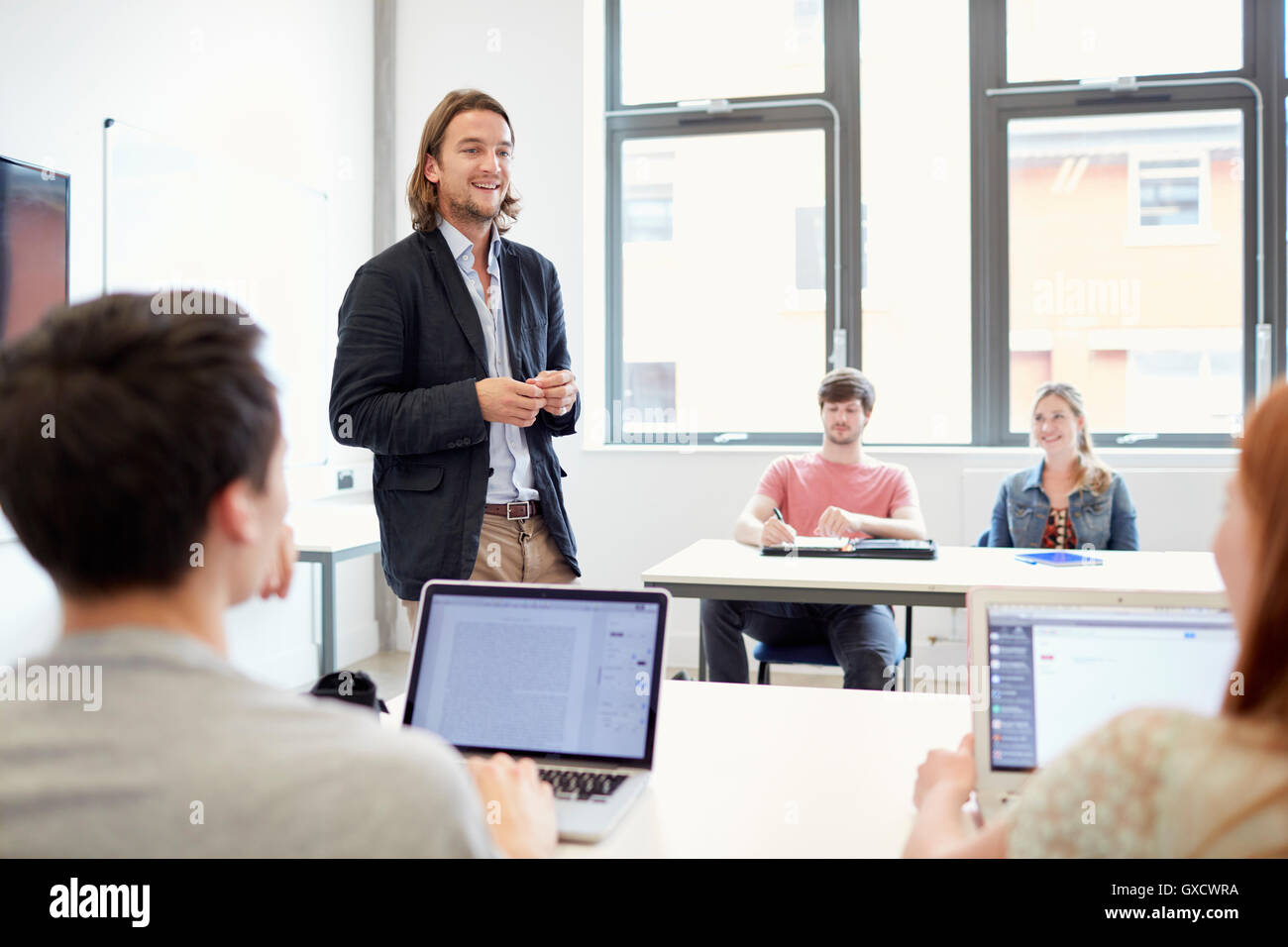 Male lecturer teaching students using laptops in higher education