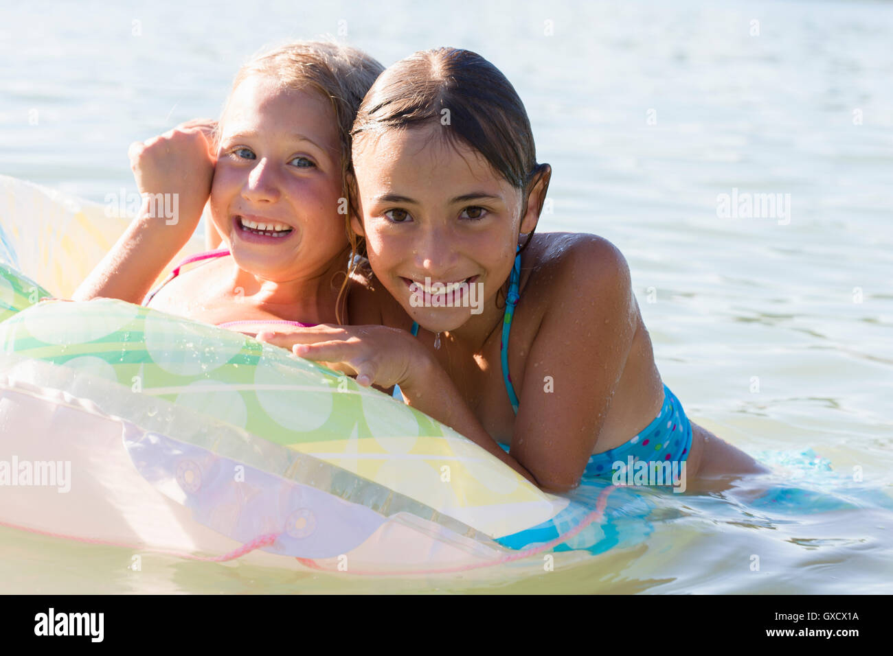 Portrait of two sisters playing with inflatable ring in Lake Seeoner See, Bavaria, Germany Stock Photo