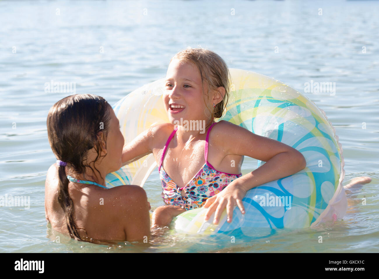 Two sisters playing with inflatable ring in Lake Seeoner See, Bavaria, Germany Stock Photo