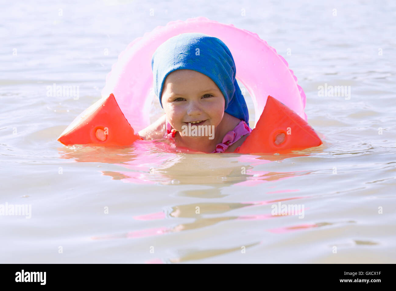 Portrait of female toddler wearing rubber ring and inflatable armbands in Lake Seeoner See, Bavaria, Germany Stock Photo