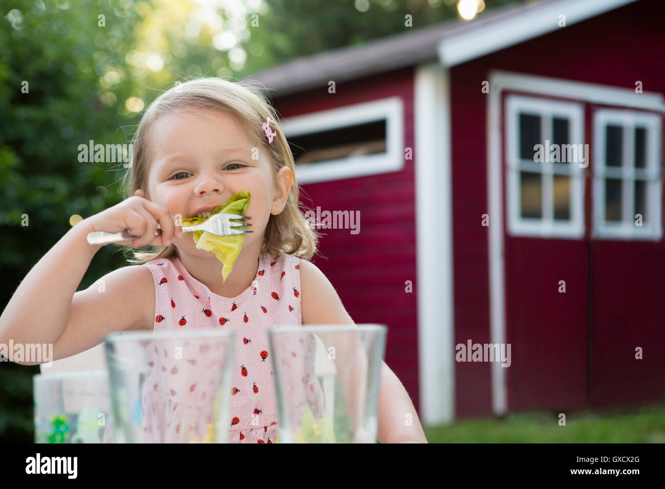 Portrait of female toddler eating salad in garden, Bavaria, Germany Stock Photo