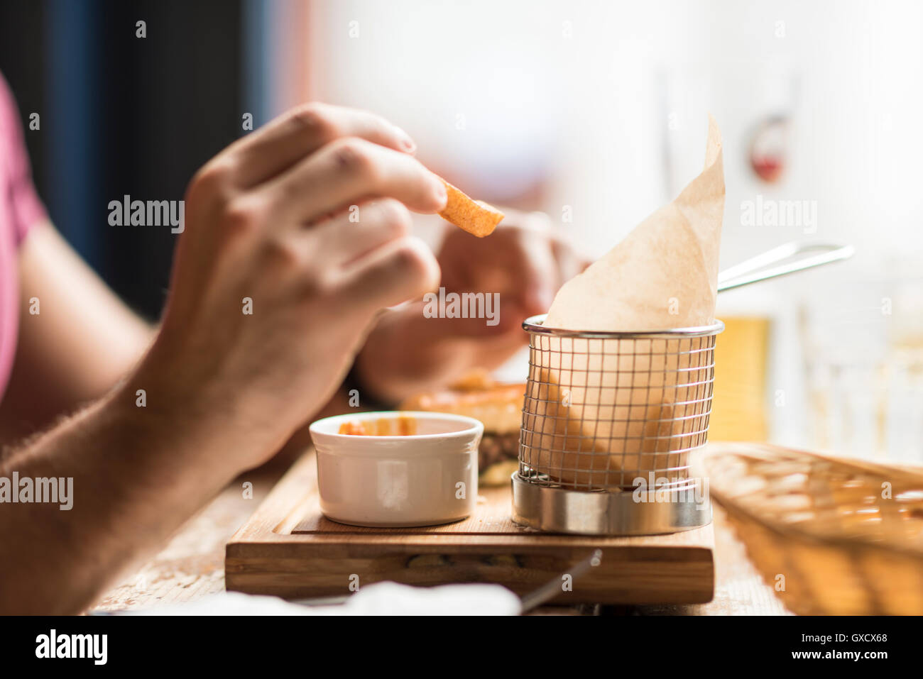 Hand of young man eating chips in restaurant Stock Photo